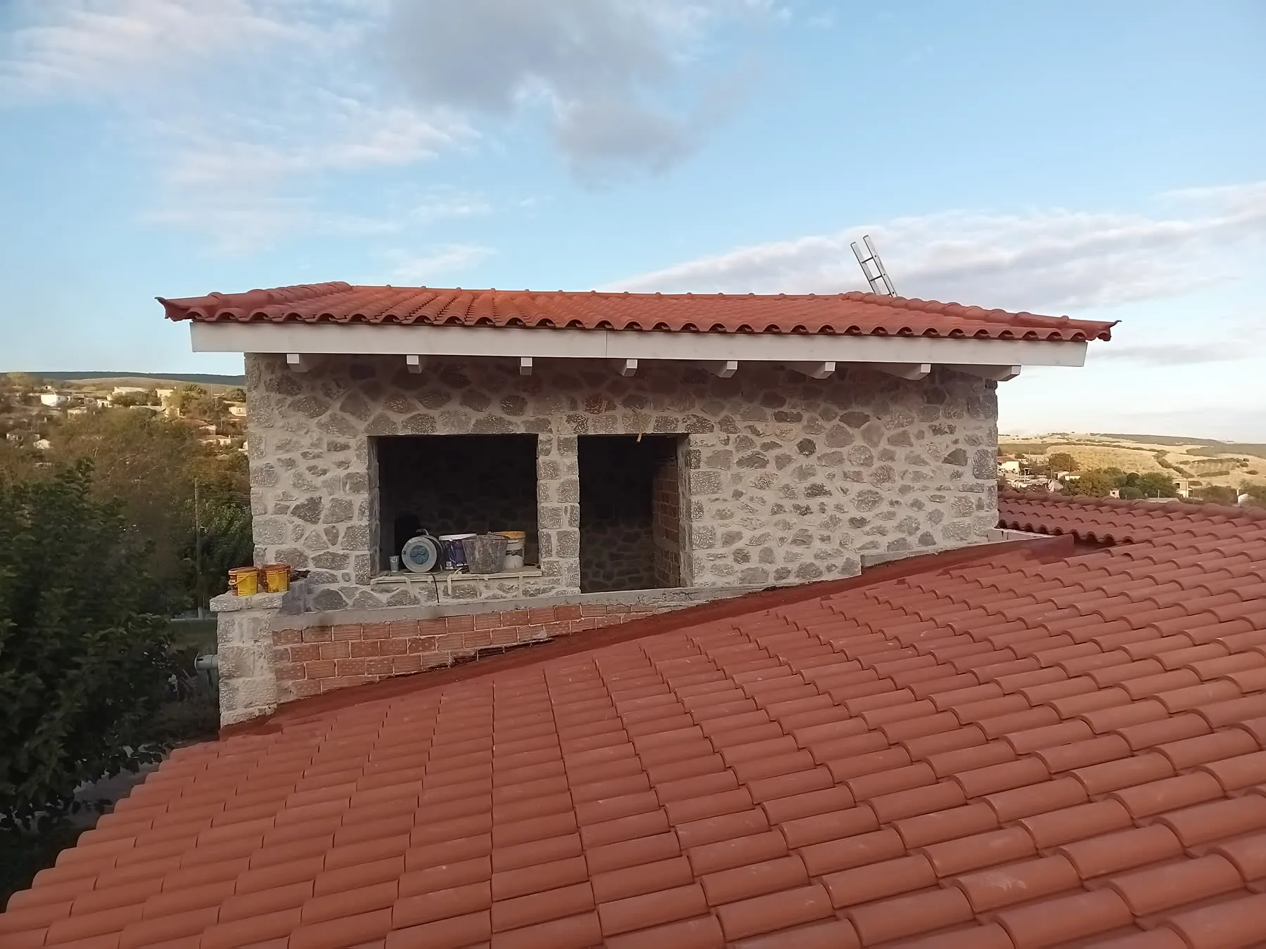 Red tiled roofs on a stone building that is still under construction
