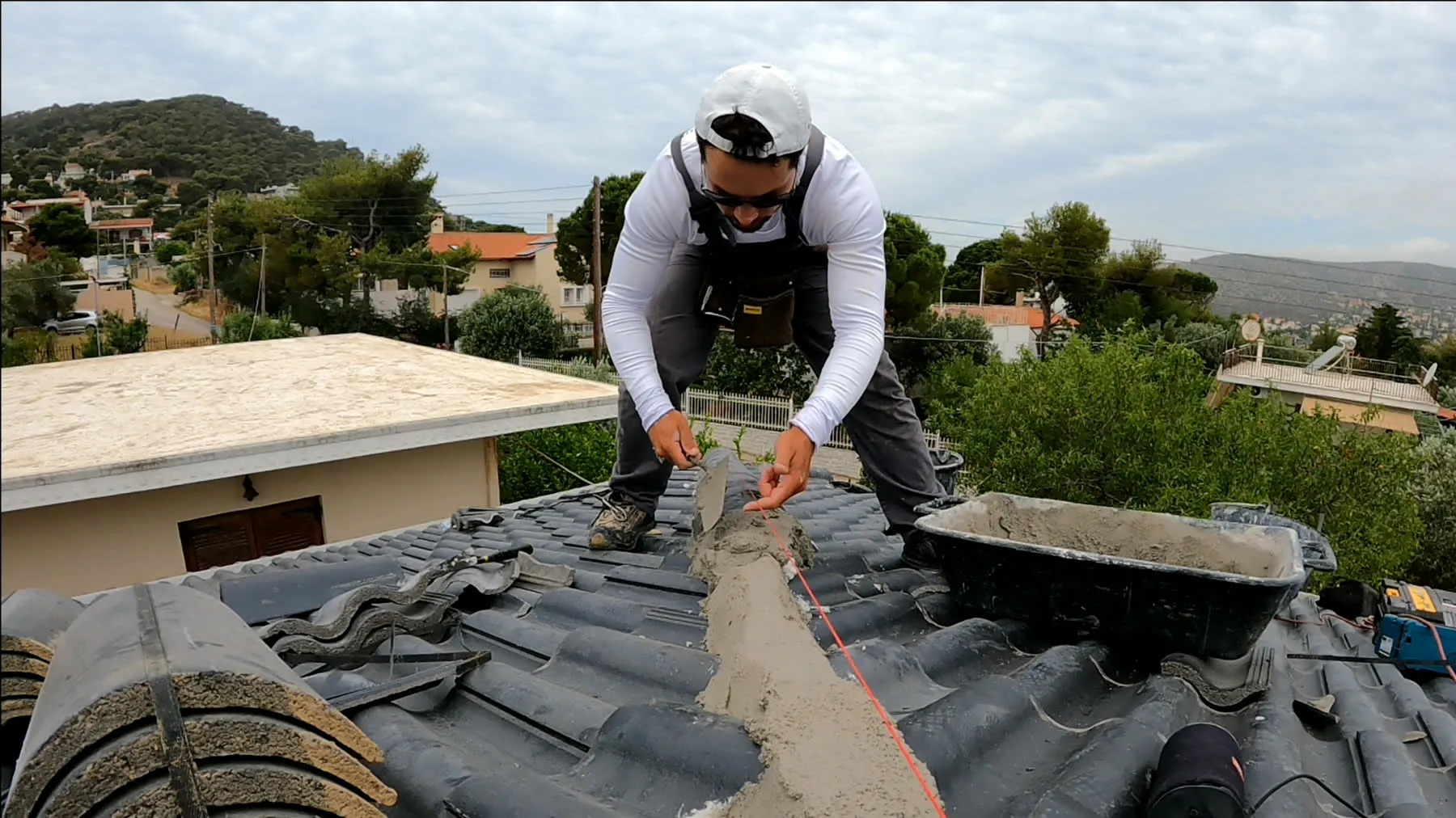 The founder working with mortar along the ridge of an existing tiled roof