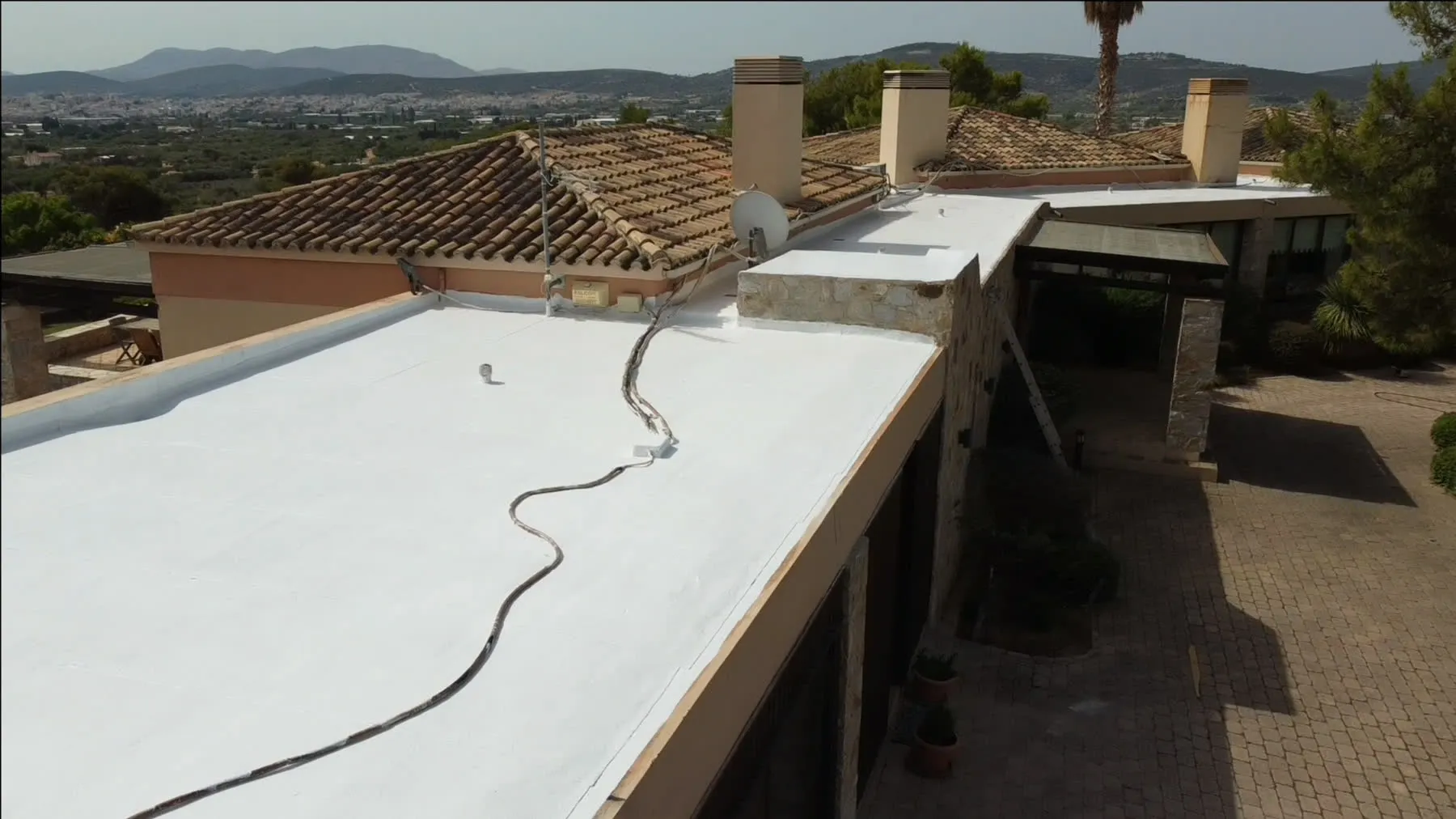 A white-coated terrace surface beside tiled roofs